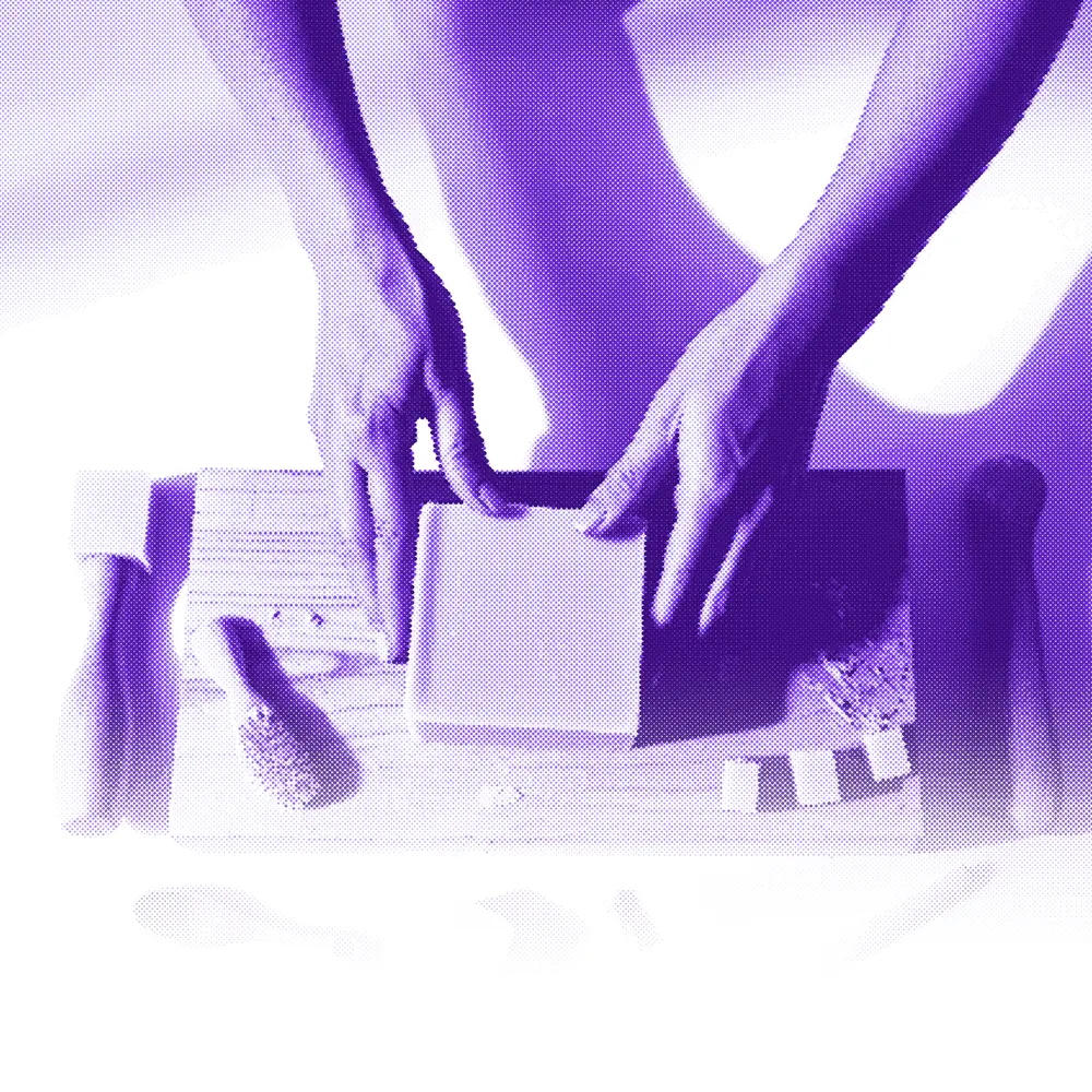 A maker's hands smoothing a fresh block of handmade soap on a wooden workbench
